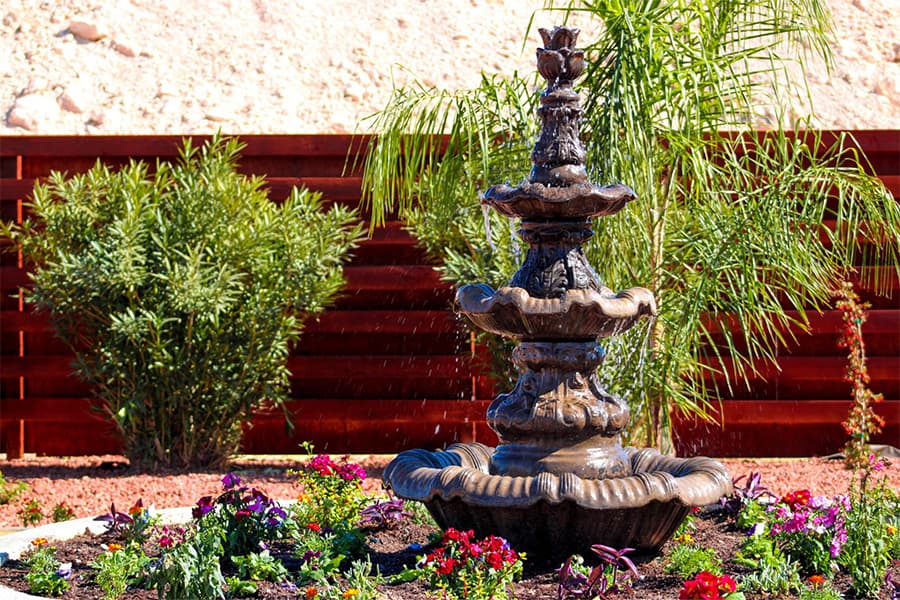 Discover a serene oasis in Nevada with a stone fountain, vibrant flowers, and red fence—a perfect end to ATV tours near the Colorado River.